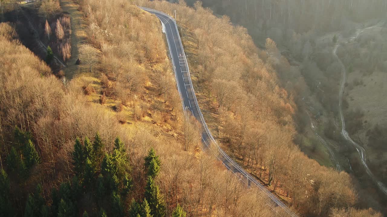 Aerial photograph of a curved road stretching into a steep, mountainous embankment
