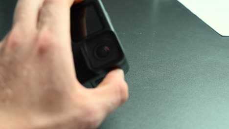 un cineasta sostiene una cámara de acción entre sus dedos con una lente, un dispositivo electrónico resistente al agua