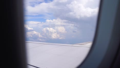 Looking-outside-airplane-window-flying-through-beautiful-skies