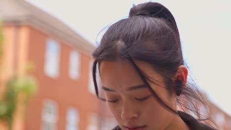 close up of young woman exercising running along urban street wearing wireless earbuds