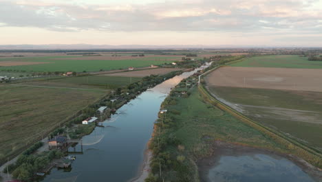 Luftaufnahme-Von-Fischerhütten-Am-Ufer-Der-Mündung-Bei-Sonnenuntergang,-Italienische-Fischereimaschine,-Genannt-„Trabucco“,-Lido-Di-Dante,-Ravenna-In-Der-Nähe-Des-Comacchio-Tals