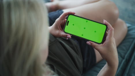mujer sosteniendo un teléfono con una pantalla verde