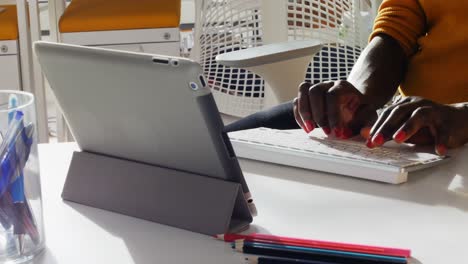 mid section of female executive typing on keyboard at desk