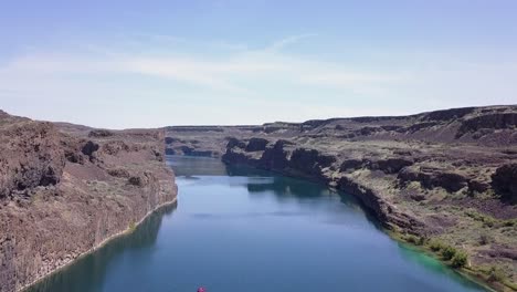 aerial rises over lone boat in deep blue lake in wa state scablands