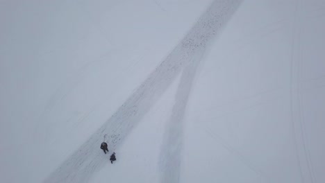 birds eye view of people having fun on frozen lake during their hike in spite of cloudy and overcast weather