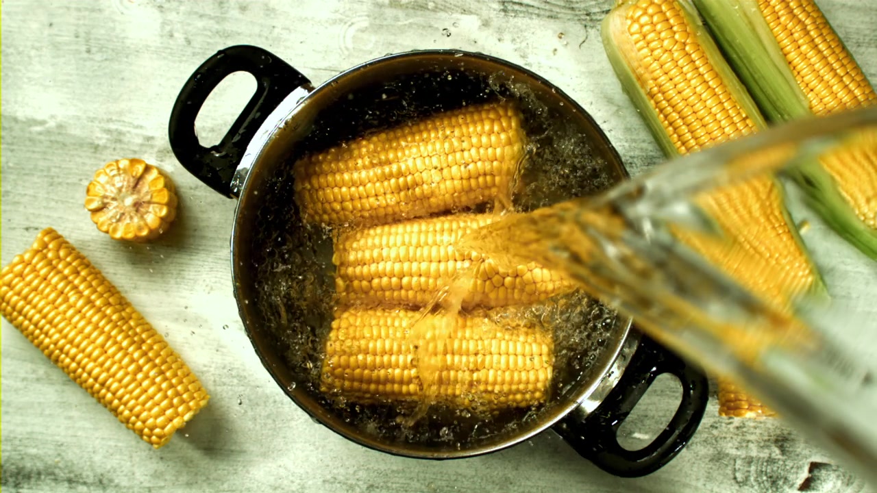 Slow Motion of Water Pouring Over Fresh Corn on the Cob in a Pot