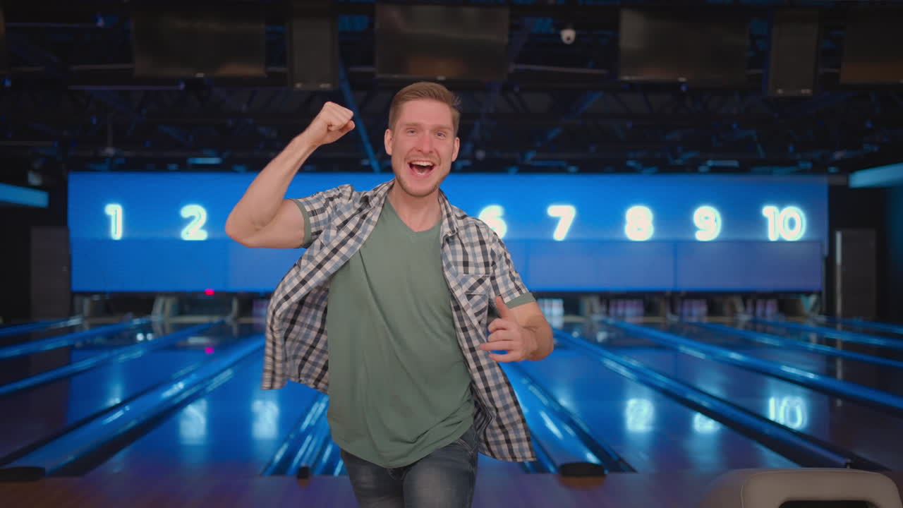 Portrait A young man jumps joyfully looking into the camera celebrate the victory in slow motion. Throw in the bowling alley to make a shoot. Victory dance and jump with happiness.