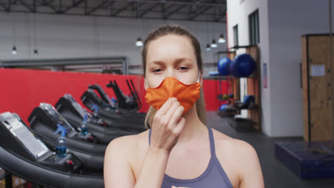 mujer caucásica en forma usando máscara facial en el gimnasio