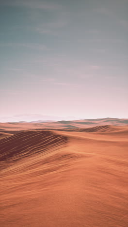 arid landscape with sand dunes under a pink sky