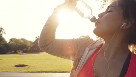 fitness woman drinking water outdoors in park