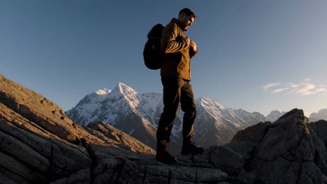 hiker on rocky mountain peak with snow-capped mountains