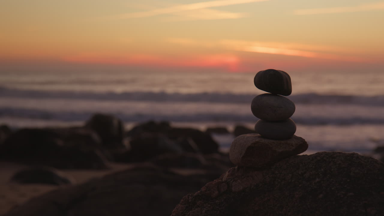 Artistic stone stack on sandy beach during sunset
