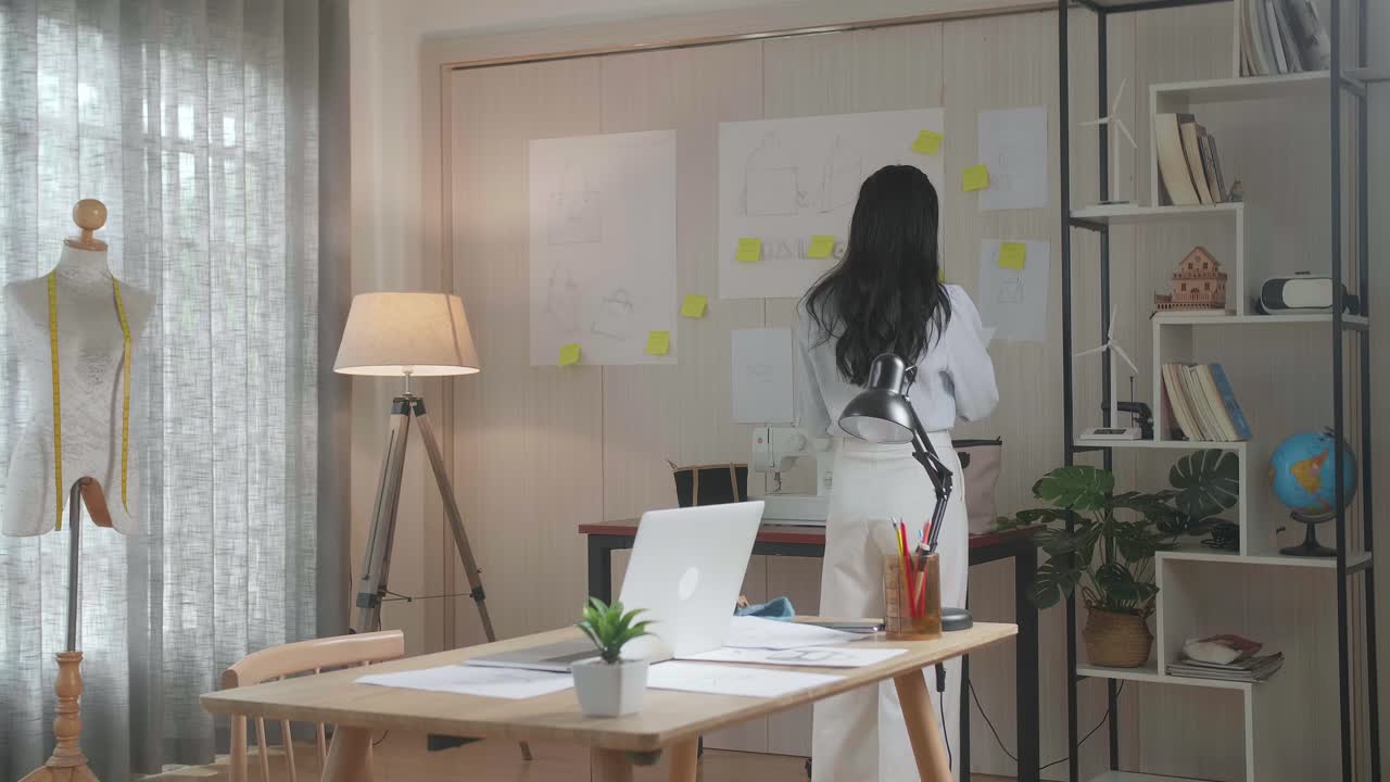 아시아 여성 디자이너는 레이아웃을 보면서 생각하고 사무실에서 고 있습니다.