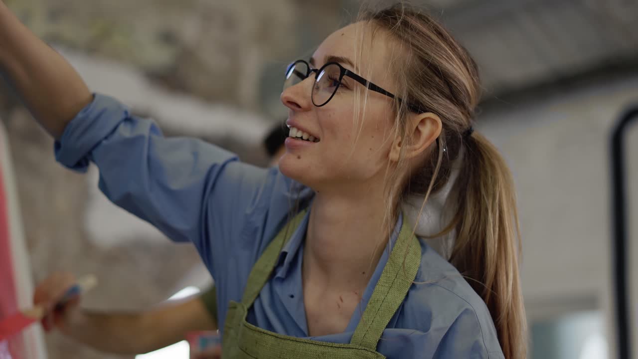 una pareja alegre pinta en un lienzo en un estudio de arte