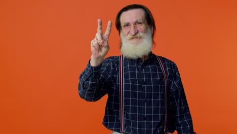 smiling senior man with gray hair and white beard gives peace sign