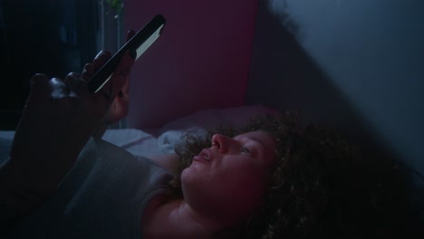 woman using smartphone in bed at night