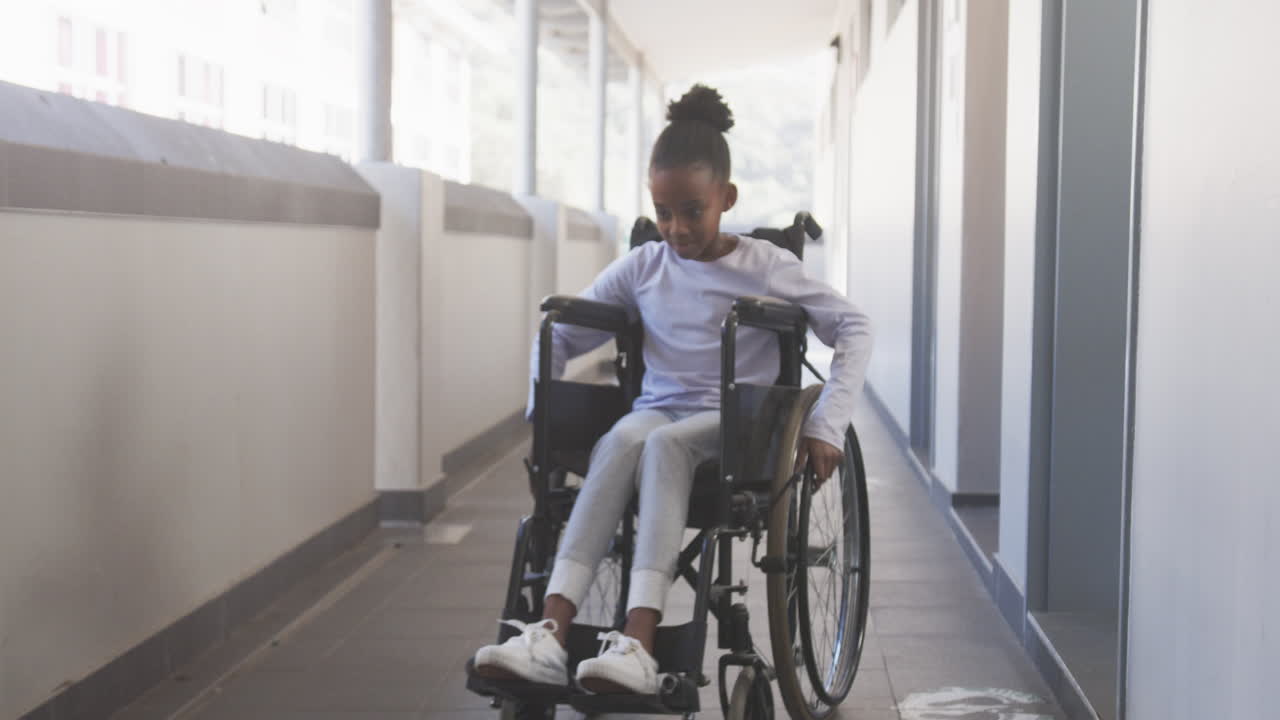 Navigating school hallway, African American girl in wheelchair moving independently, smiling confide