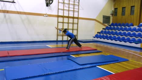 a moving shot of a guy doing a gymnastics sequence including a round off, back hand spring, and a back and front flip on the floor