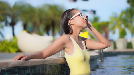 Hermosa-Mujer-En-Traje-De-Baño-Amarillo-De-Pie-En-La-Piscina-Soleada