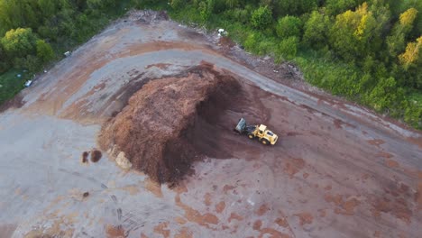 Front-end-loader-parked-in-front-of-a-large-pile-of-sawdust