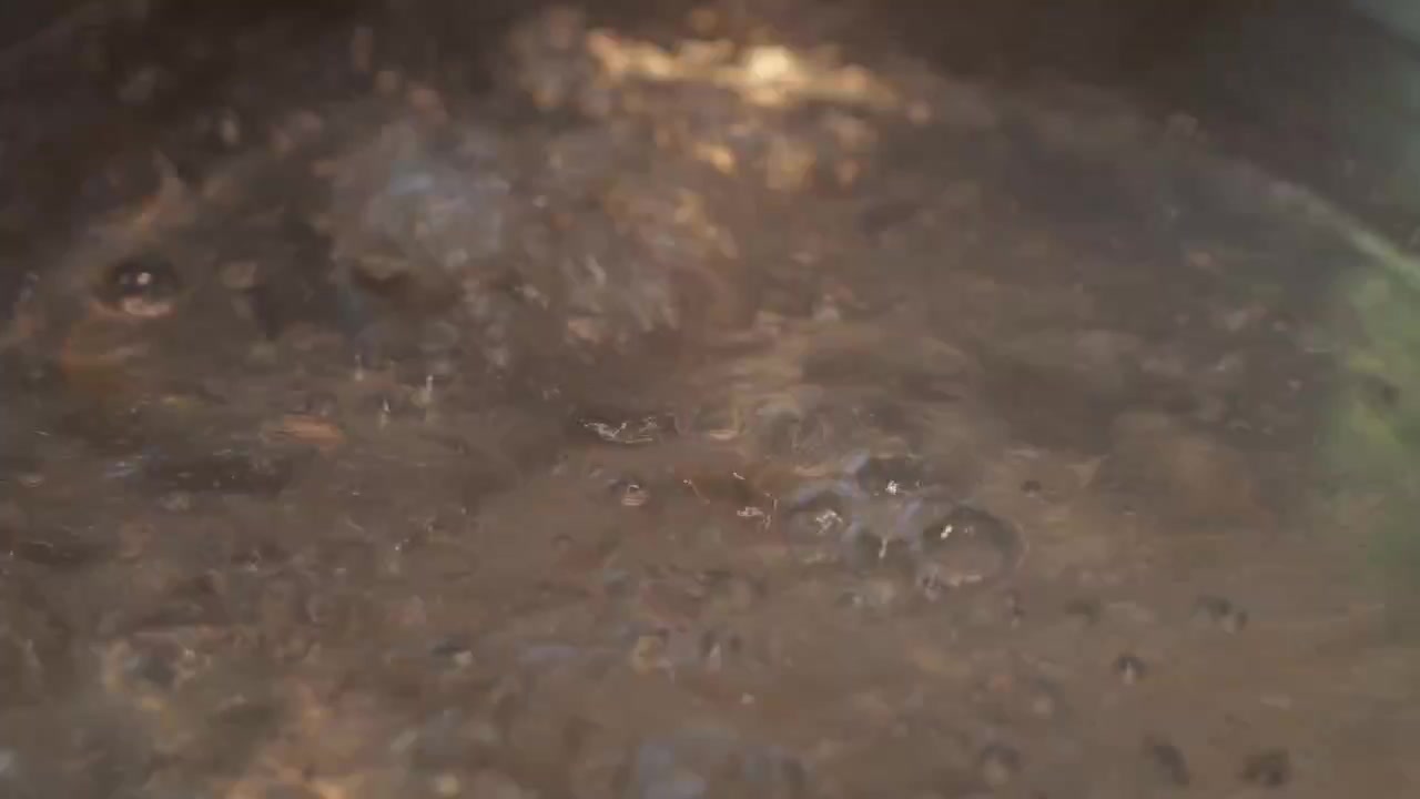 Close-up of a steaming shabu shabu hot pot with vigorously bubbling broth, rising steam, and a rich savory soup base ready for cooking.