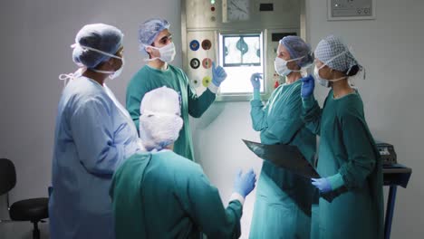 Video-of-diverse-group-of-surgeons-discussing-x-ray-in-operating-theatre-before-operation