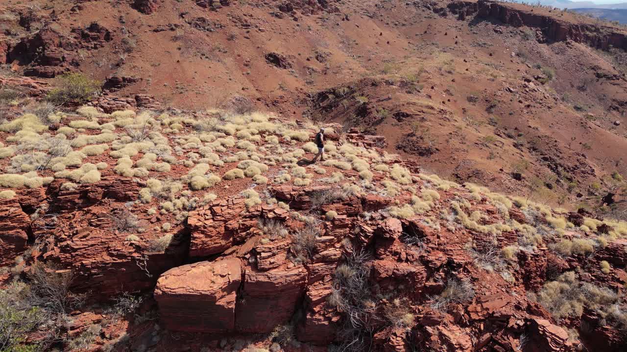 toma aérea en órbita de un excursionista masculino en las montañas rojas durante un día soleado en el parque nacional de karijini