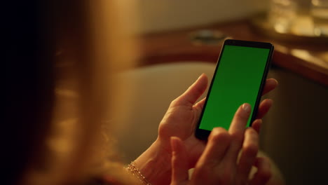 Hand-touching-greenscreen-smartphone-closeup.-Woman-swiping-cellphone-on-jet.