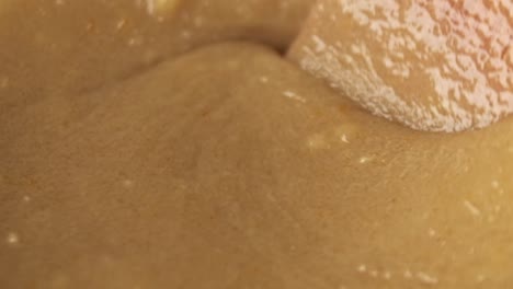 macro cámara lenta de revolver el ingrediente alimentario usando una espátula de madera