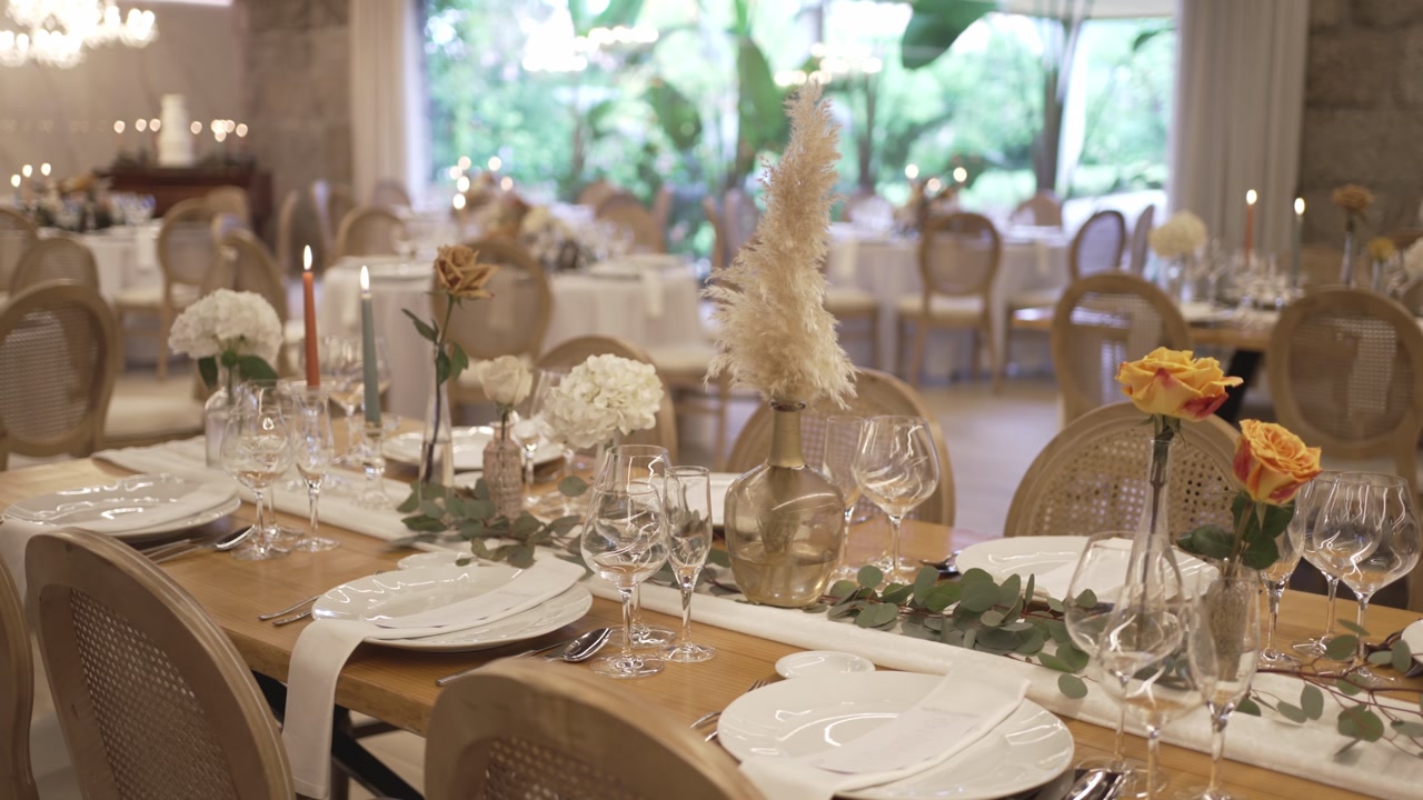 Long wooden wedding table with pampas grass centerpieces roses glassware and eucalyptus garland