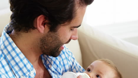 cerca de un padre feliz alimentando con botella a su bebé