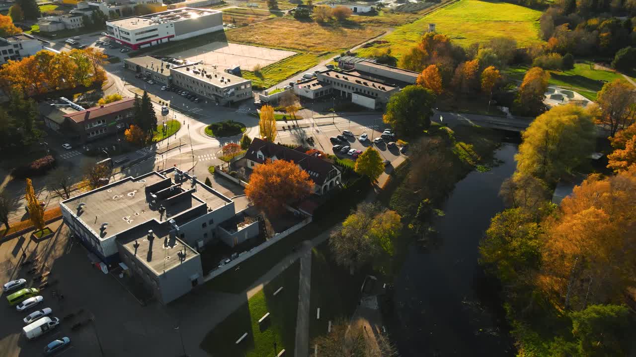 Aerial drone video of Laagri small town or neighbourhood during autumn sunny day or sunset with trees that have yellow leaves on the,. Cars and vehicles driving near Saue admisitrative center, roads