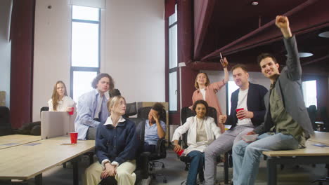 group of multiethnic colleagues watching a sportive match, cheering and supporting their team at the office 3