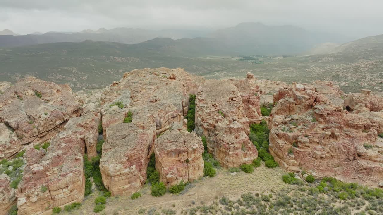 дрон летает очень высоко над скальными образованиями в пустынном ландшафте в пустыне седерберга в южной африке - на заднем плане видны горы в облаках