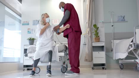 African-american-male-doctor-checking-blood-pressure-of-caucasian-female-patient-at-hospital