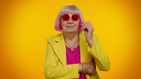 mujer mayor elegante con cabello rosa y gafas de sol