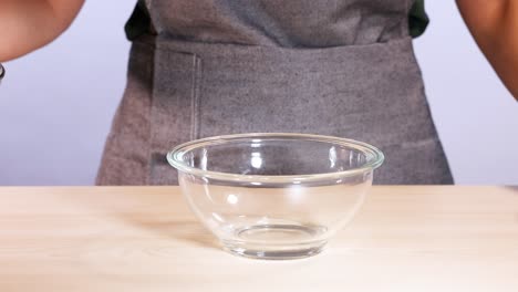 person pouring chocolate chips into a glass bowl