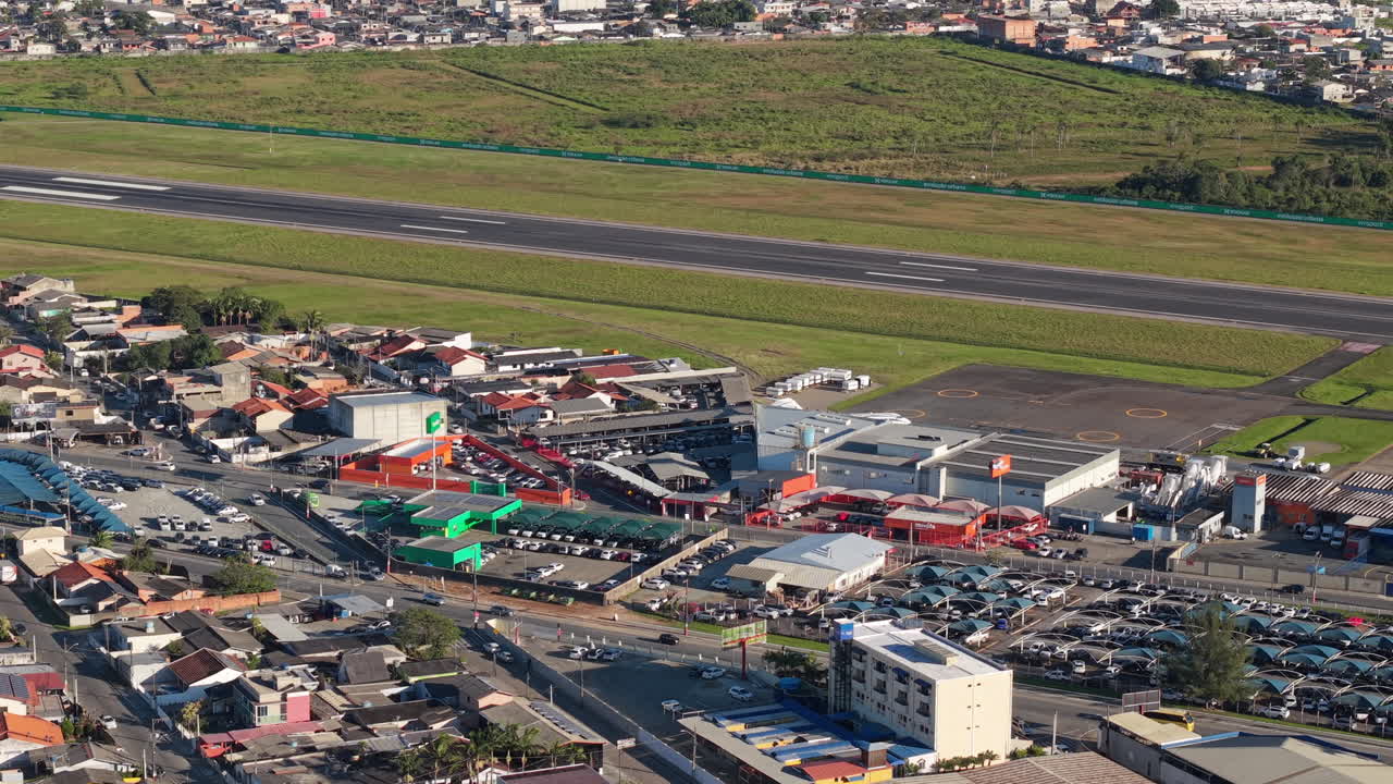 Aerial view of Navegantes International Airport, Santa Catarina, Brazil, showing the main runway, terminal buildings, nearby streets, parking areas, and surrounding urban landscape