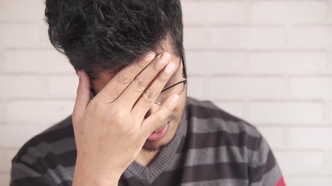 두통 을 고 있는 스트레스 를 받는 젊은 남자