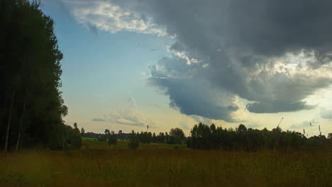 Cinematic-timelapse-of-the-sun-setting-over-a-grassy-field-with-trees-and-wheat-in-the-foreground,-time-lapse