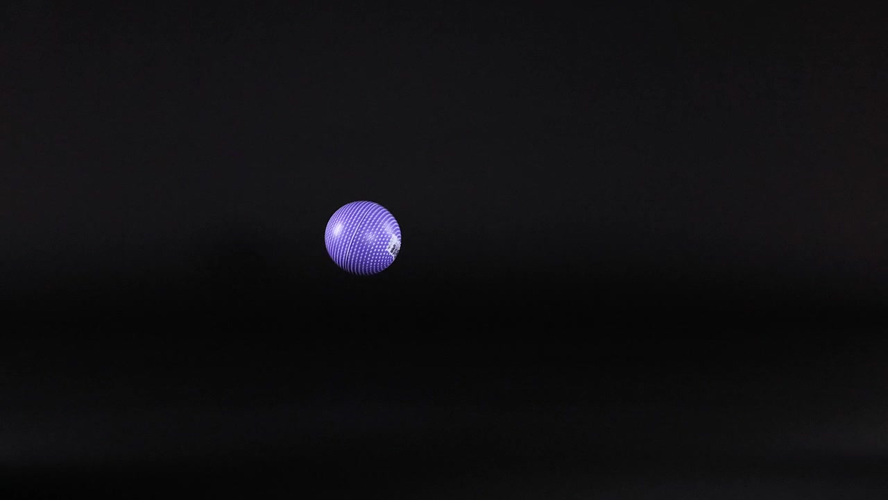 A purple ball bounces in a dark space