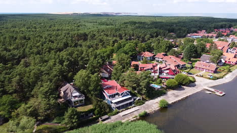 beautiful town of pervalka surrounded by dense pine forest on sunny day, aerial drone view