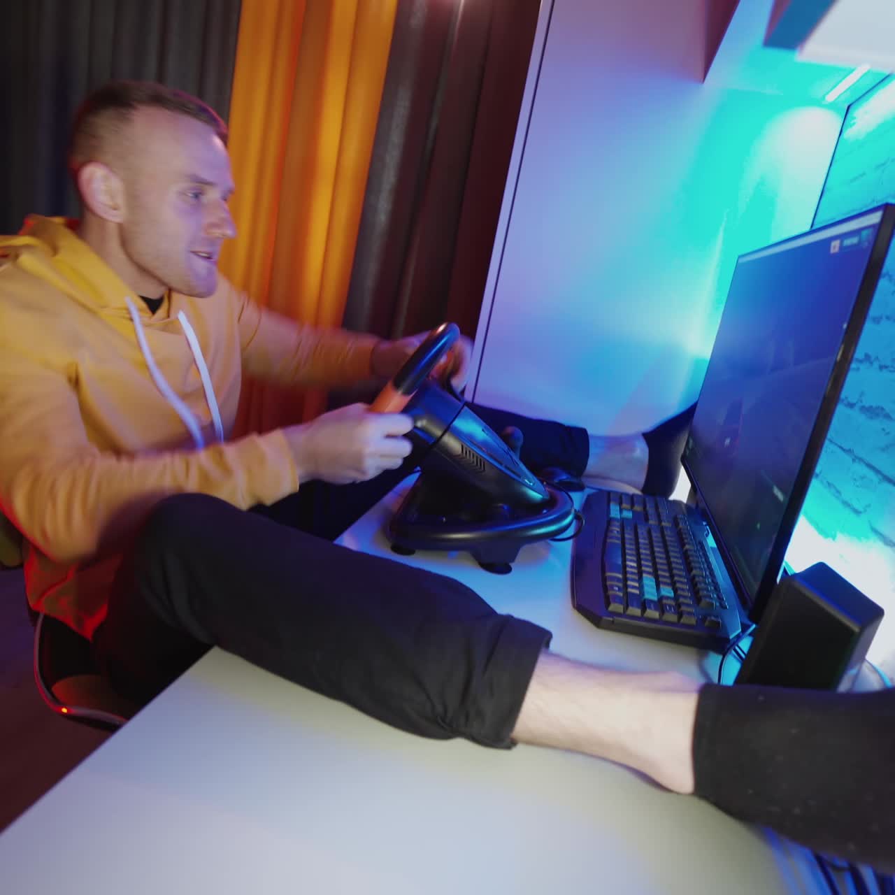 Uomo che gioca con il volante a casa. Giovane che gioca a un videogioco di corse automobilistiche a casa.