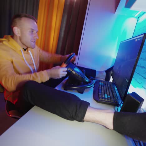 . man playing with steering wheel at home. young man playing car racing video game at home