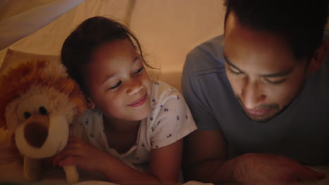 father and daughter reading story in a play tent