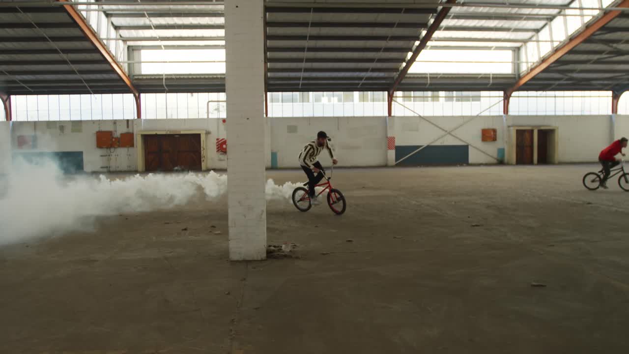 jinetes de bmx en un almacén vacío usando una granada de humo