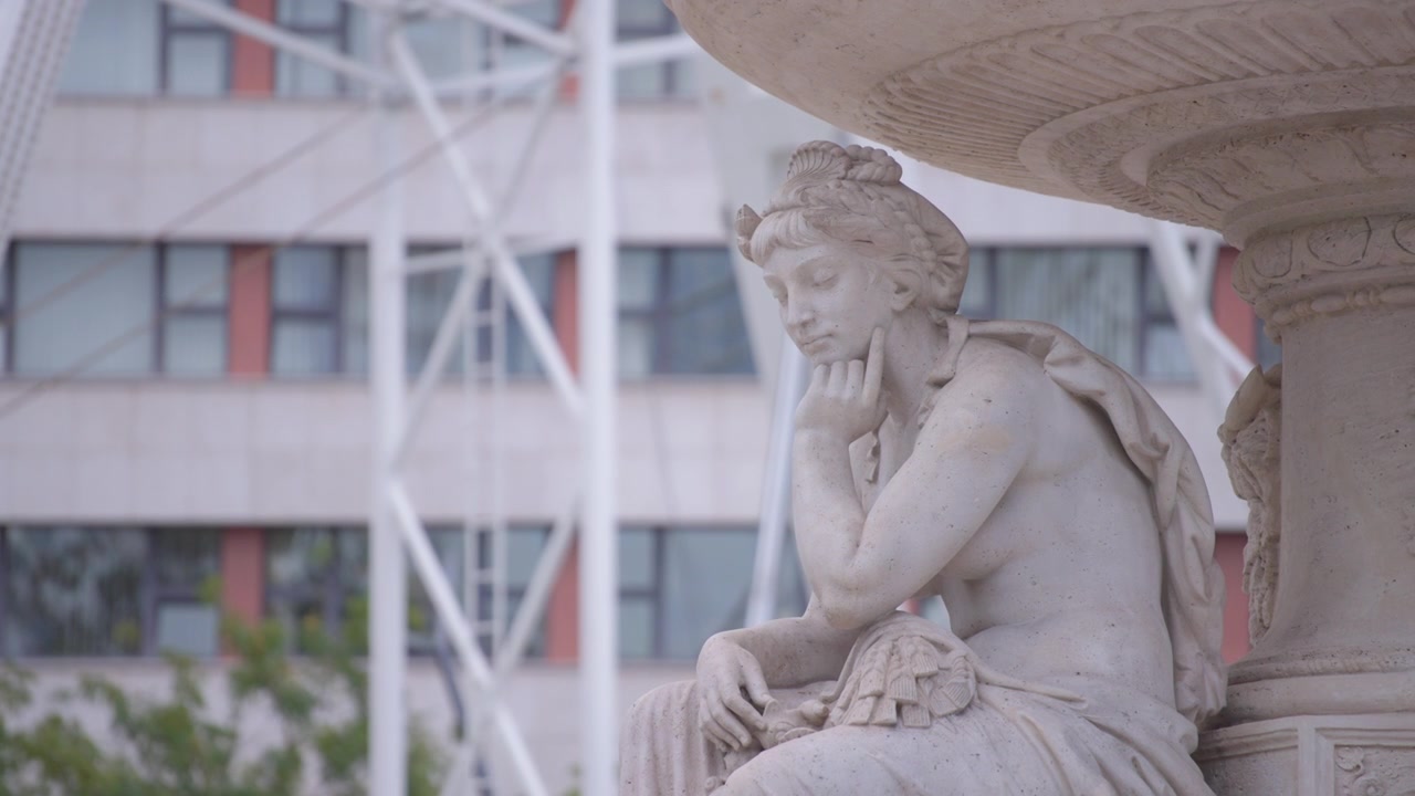 Una statua femminile bianca e una ruota rotante