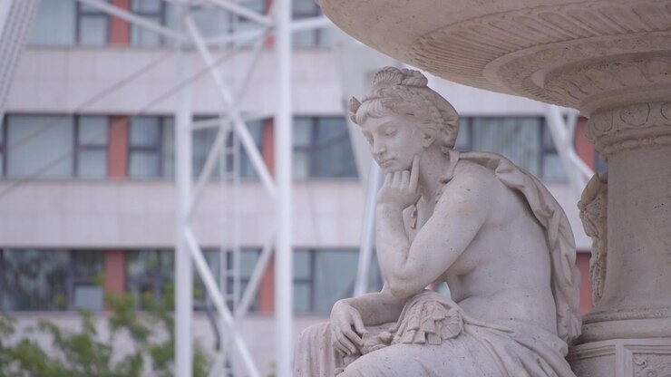 Una statua femminile bianca e una ruota rotante