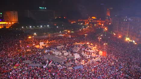 fireworks go off above protestors gathered in tahrir square in cairo egypt at a large nighttime rally