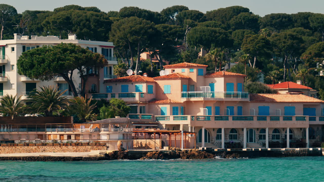Distant view of multiple villas on the shore with the waves of the sea crashing on the rocks